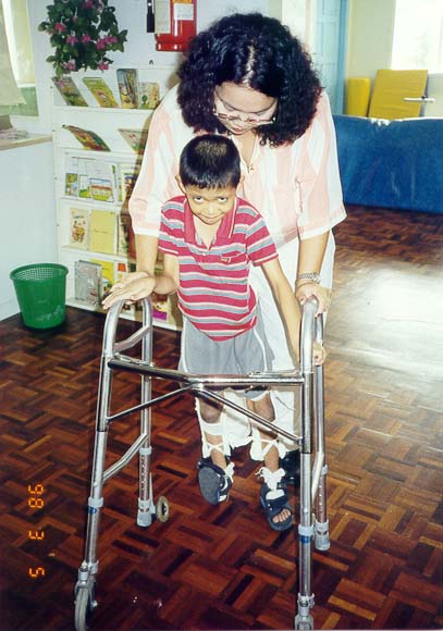 Teacher Fara showing Mohd Faizul Iswan on how to use the walker during one of the Physio Therapy Session.